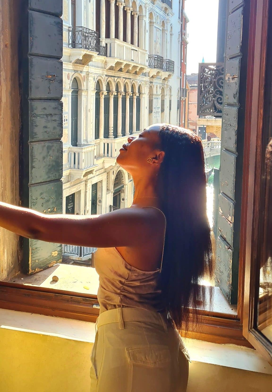 Femme de dos admirant la lumière traversant les bâtiments de Venise, symbolisant l'introspection, l'amour authentique et l'exploration des émotions